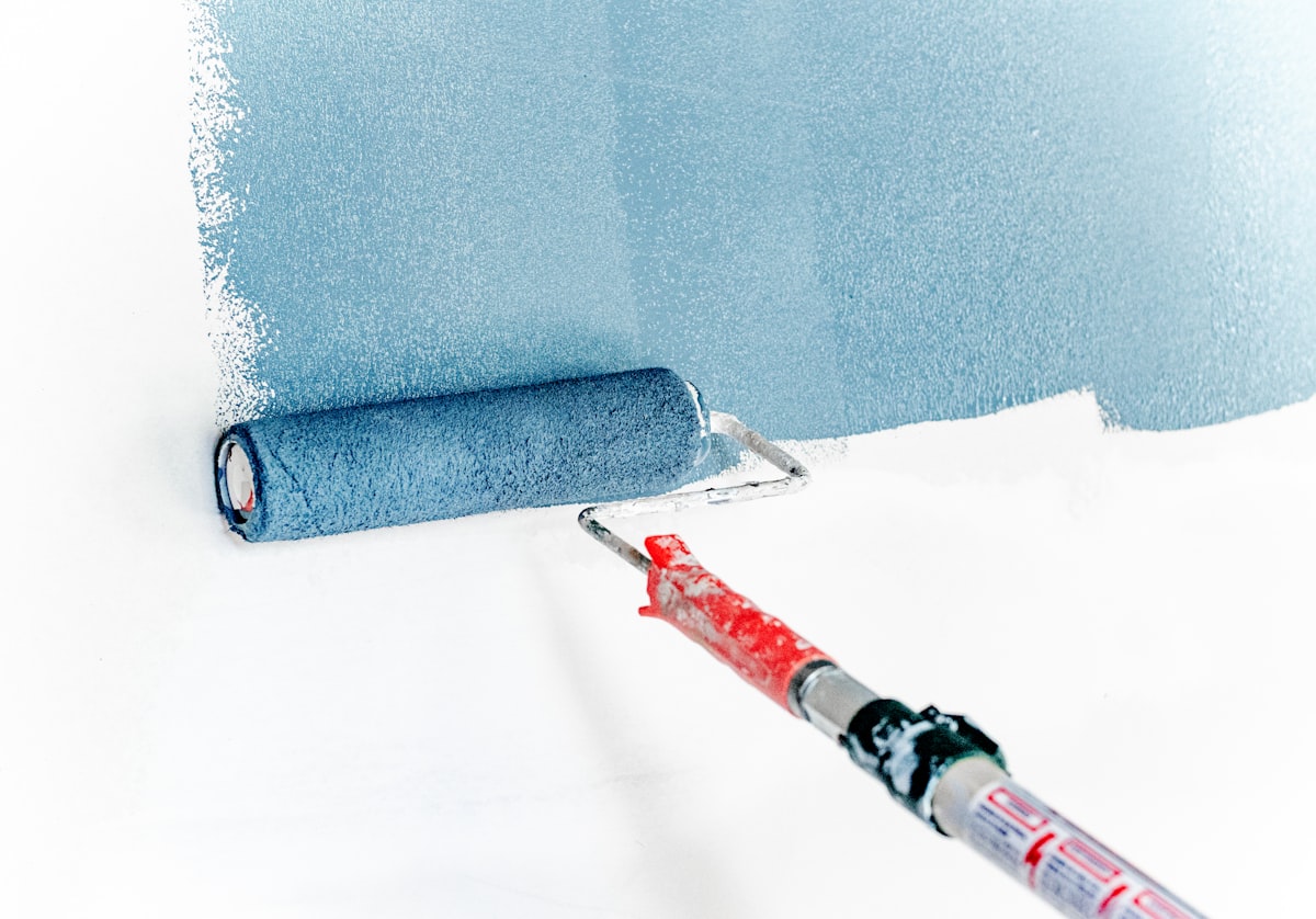 Paint roller applying blue paint to a wall